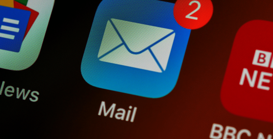 Um close-up da tela de um smartphone mostrando o ícone do aplicativo Mail com um emblema de notificação vermelho exibindo dois e-mails não lidos, possivelmente lembretes para enviar nota fiscal. Os ícones de aplicativos próximos estão parcialmente visíveis.