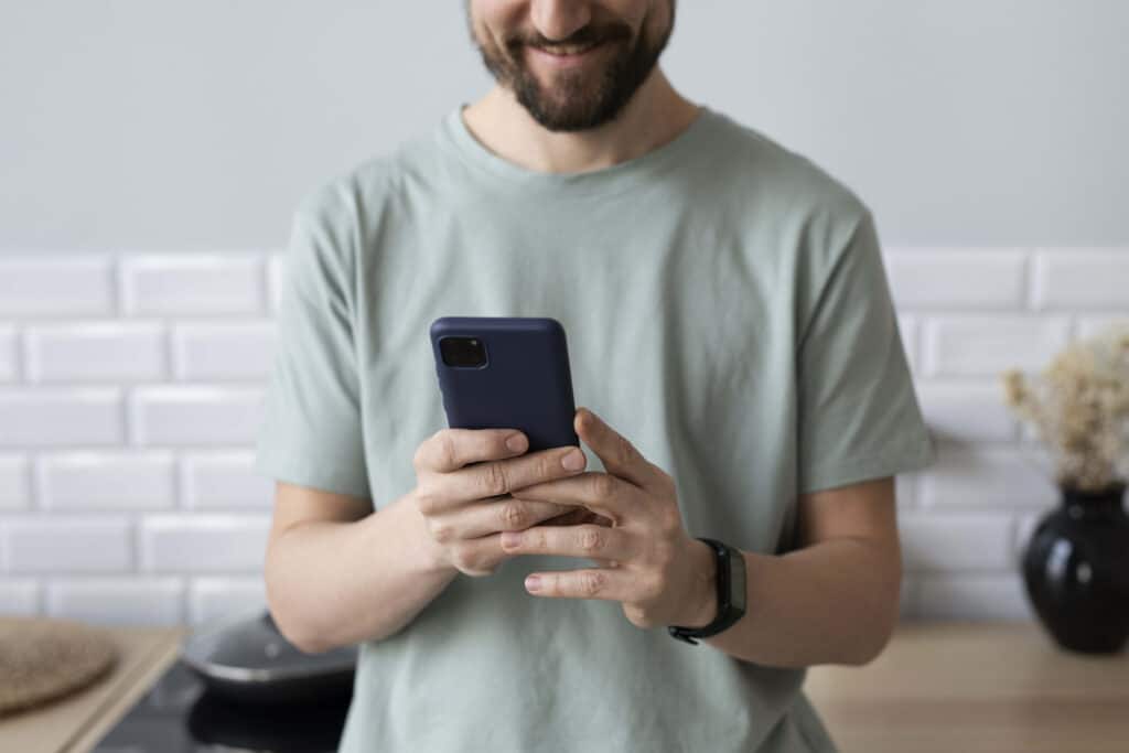 Emitir e pagar guia DAS: jovem branco de barba curta segundo um celular.