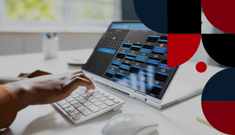 Pessoa digitando em um teclado branco, olhando para um laptop exibindo um calendário digital com vários compromissos. O espaço de trabalho é claro, com formas abstratas vermelhas e pretas parcialmente visíveis à direita.