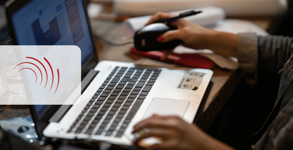 Uma pessoa usando um laptop, com uma mão no teclado e a outra segurando um mouse de computador, parece concentrada em cálculos de irpj/csll. Uma sobreposição transparente com um ícone de onda sonora vermelha é visível no lado esquerdo da imagem.