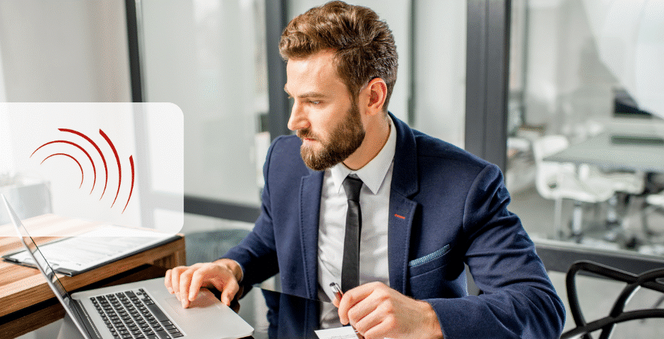Um homem de terno azul está sentado em uma mesa trabalhando em um laptop em um escritório moderno, revisando documentos do ECF 2025. Ele segura uma caneta e olha para a tela. Há papéis e um notebook sobre a mesa, com um ícone de onda sonora vermelha aparecendo no lado esquerdo da imagem.