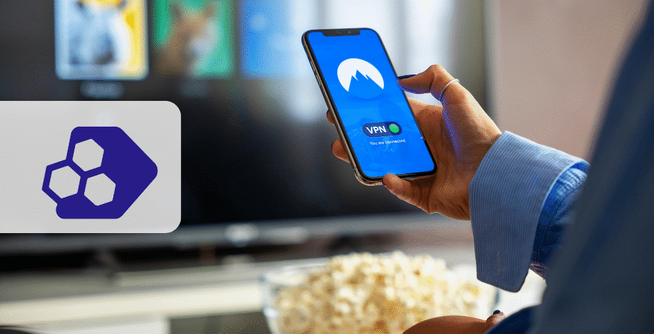 Uma pessoa segurando um smartphone com um aplicativo VPN API NFCom aberto em frente a uma tela de TV; uma tigela de pipoca está próxima. À esquerda, há um logotipo de tecnologia hexagonal roxo em um fundo cinza.