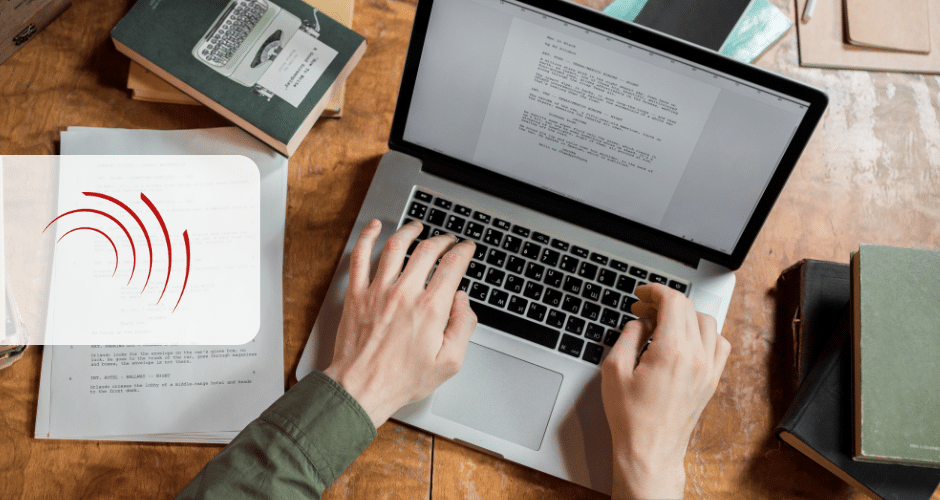 Uma pessoa digita em um laptop em uma mesa de madeira cercada por livros e papéis, possivelmente preparando uma Declaração de Regimes Específicos. Um gráfico transparente com linhas curvas vermelhas está sobreposto no lado esquerdo da imagem.