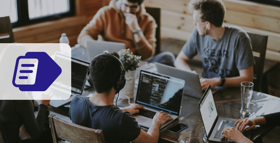 Quatro pessoas trabalham juntas em uma mesa com laptops, concentradas em suas telas - talvez analisando a Reforma Tributária para Lucro Real. Uma pessoa usa fones de ouvido. Um ícone de documento azul está sobreposto no canto esquerdo da imagem.