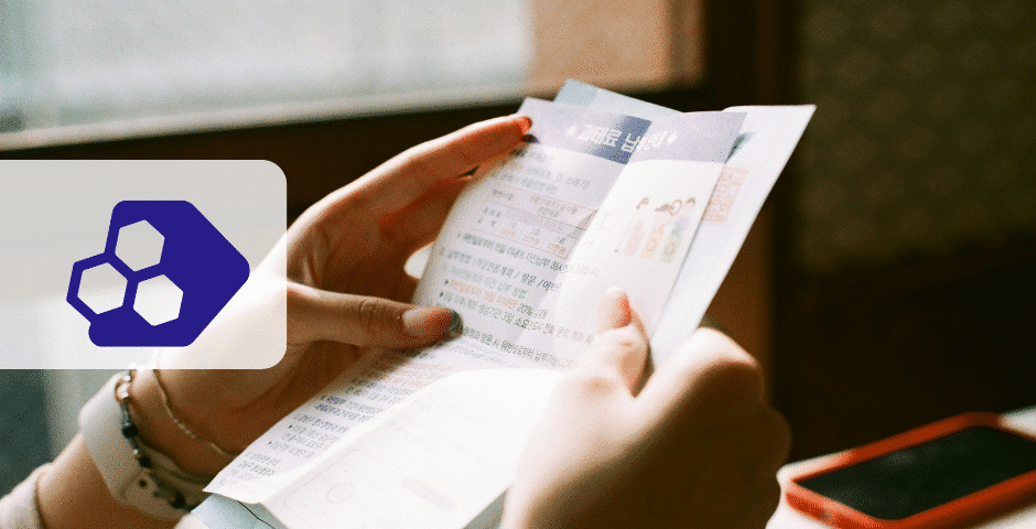 Uma pessoa segura e lê um folheto com texto em coreano perto de uma janela. Um logotipo hexagonal azul abstrato está à esquerda, e um smartphone vermelho está sobre a mesa ao fundo, apresentando informações sobre Notas Fiscais de Débito e Crédito.