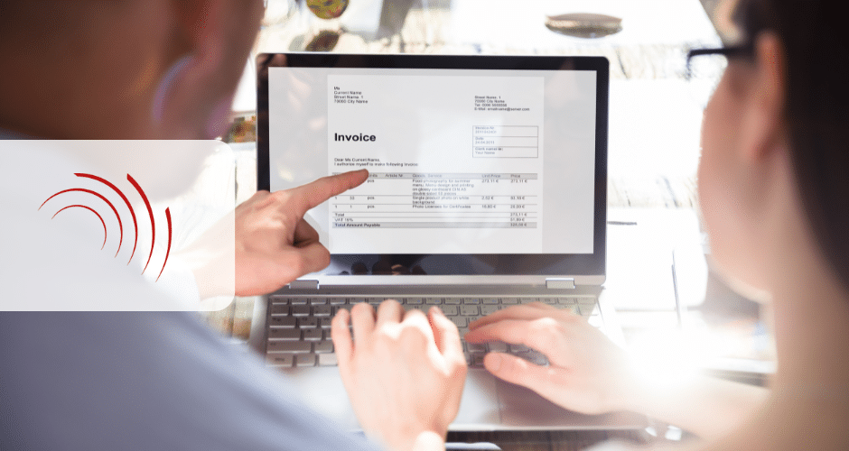 Uma pessoa aponta para uma fatura rotulada como NFSe Nacional exibida na tela de um laptop enquanto outra usa o teclado, sugerindo uma discussão ou revisão do documento da fatura.