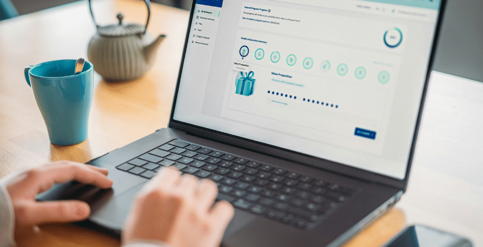 Uma pessoa usa um laptop em uma mesa de madeira. A tela exibe um rastreador de progresso para uma pesquisa on-line sobre a Nota Técnica 2026.001 PAA. Uma caneca azul e um bule de chá estão sobre a mesa ao lado do laptop.