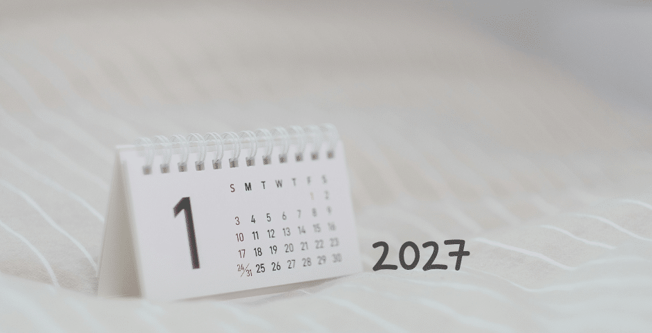 Um pequeno calendário de mesa com o mês de janeiro está sobre uma superfície de tecido macio listrado, com a frase “reforma tributária 2027” escrita em negrito ao lado.