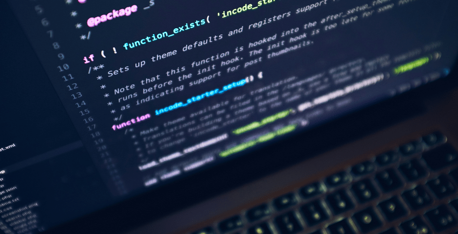 Uma imagem em close-up do teclado de um laptop, com a tela exibindo linhas coloridas de código, destacando funções PHP relacionadas ao Manual de Pagamento Dividido e comentários em um editor de código com tema escuro.